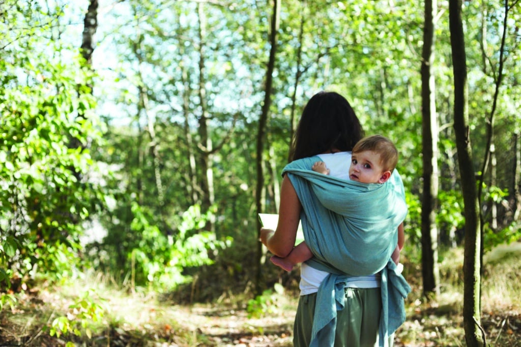 Mother with infant son in ergonomic sling, babywearing while wal
